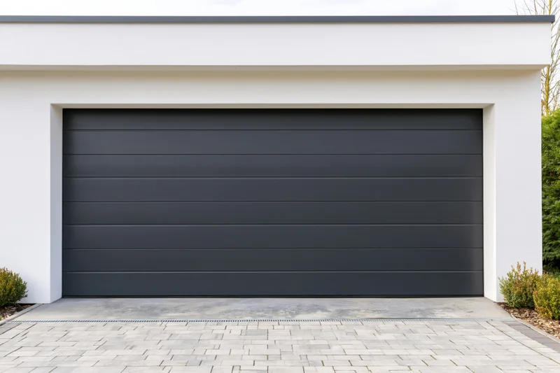 Modern residential garage with horizontal panel section door on white exterior and paved driveway