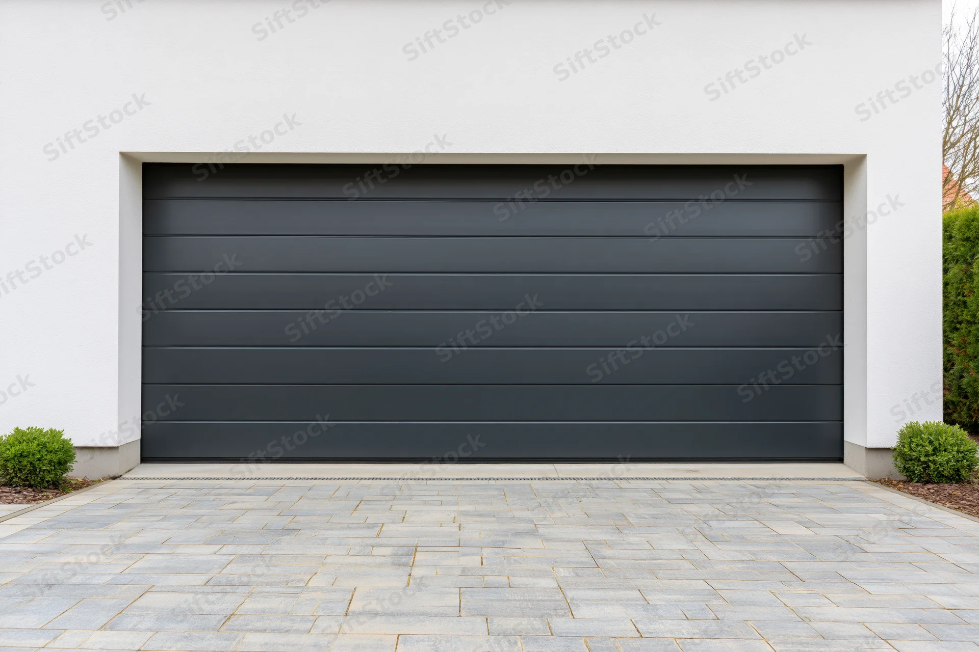 Modern residential garage with horizontal panel section door on white exterior and paved driveway