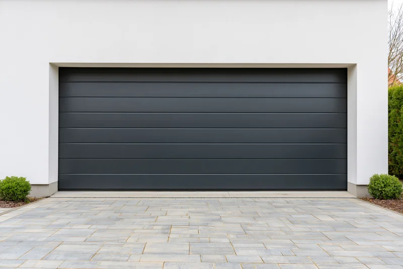 Modern residential garage with horizontal panel section door on white exterior and paved driveway
