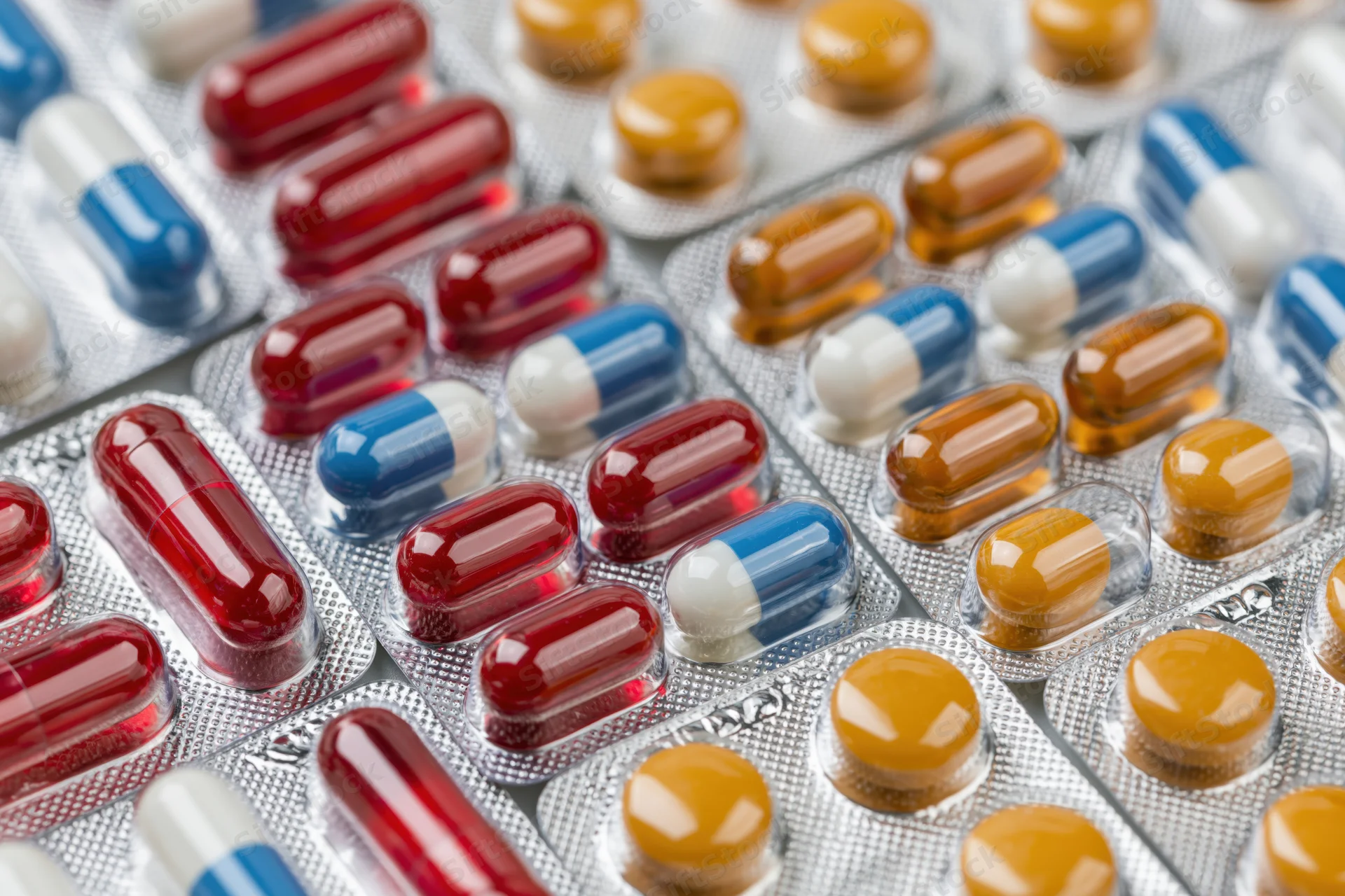 Multiple blister packs of pharmaceutical capsules and tablets arranged in close-up view