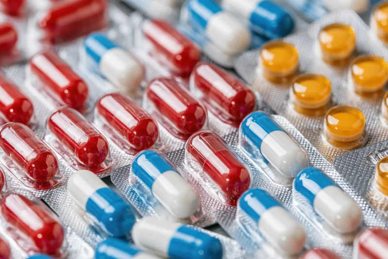 Closeup of red, blue, white and orange capsules and tablets in blister packs