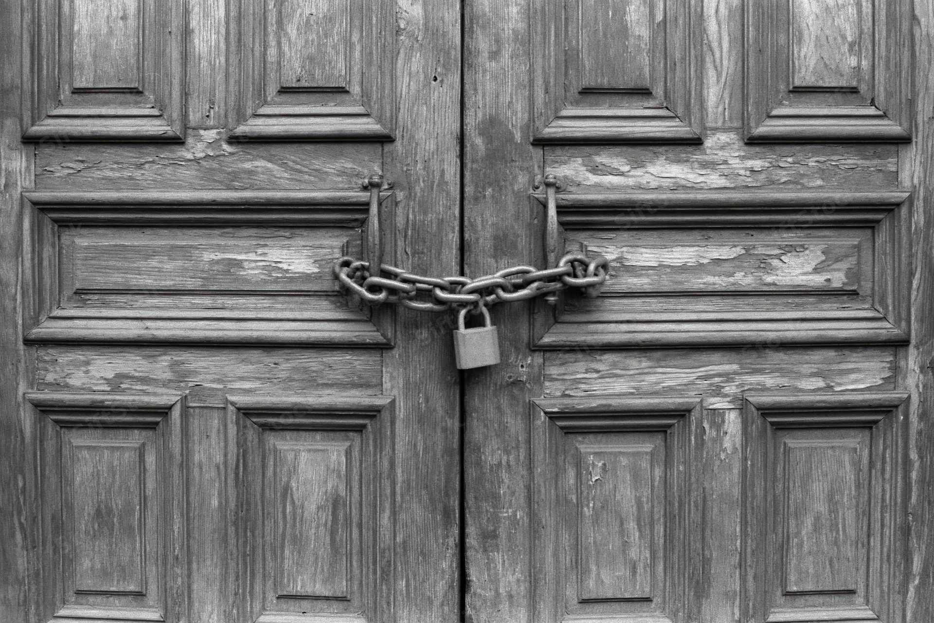 Old wooden double doors chained shut with a padlock at the center