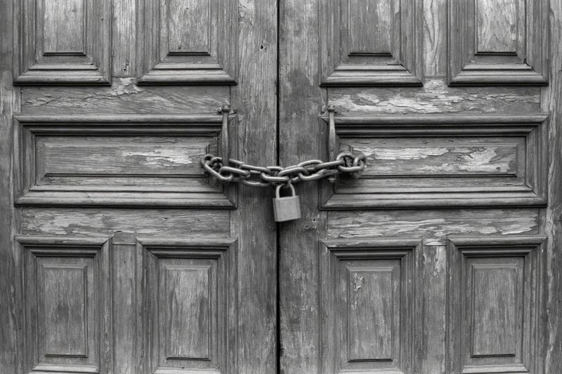 Old wooden double doors chained shut with a padlock at the center