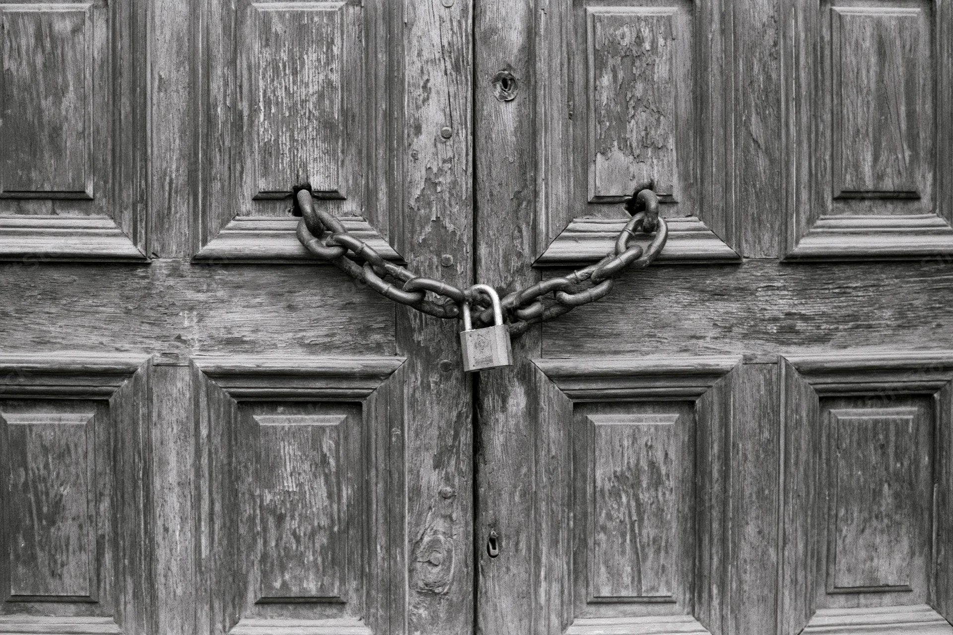 Old wooden double doors secured with a chain and padlock
