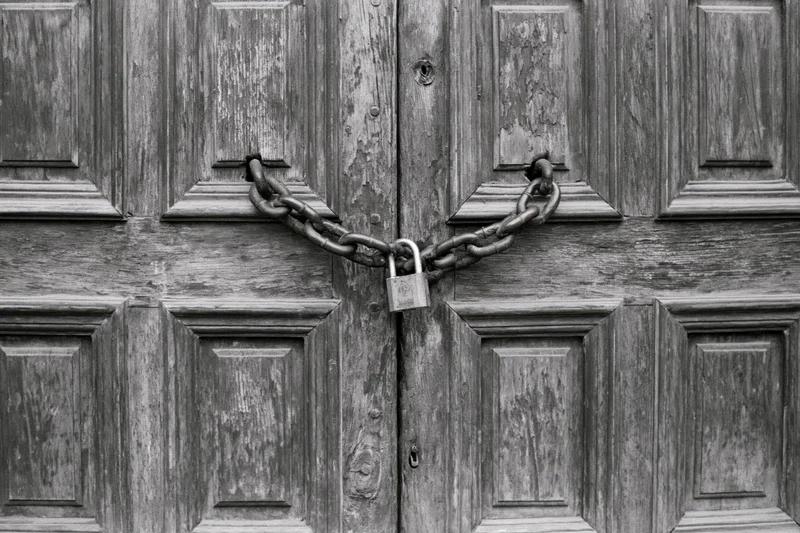 Old wooden double doors secured with a chain and padlock