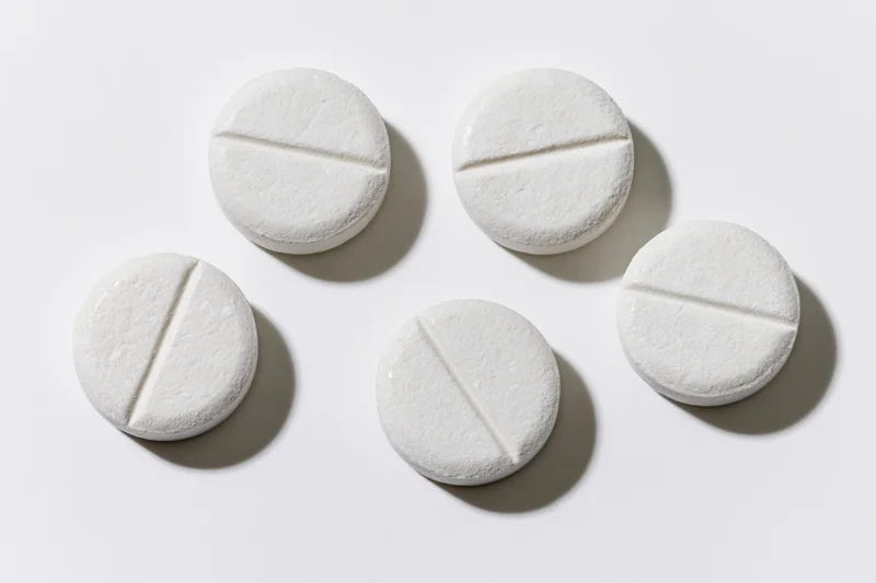 Five white scored tablets arranged in a loose grid on a plain white surface