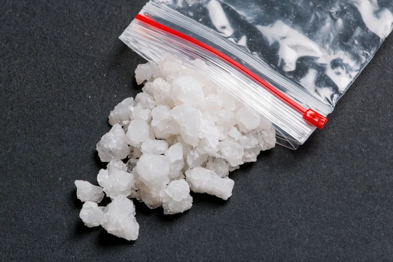 Coarse white salt crystals spilling from a clear resealable plastic bag onto a black surface