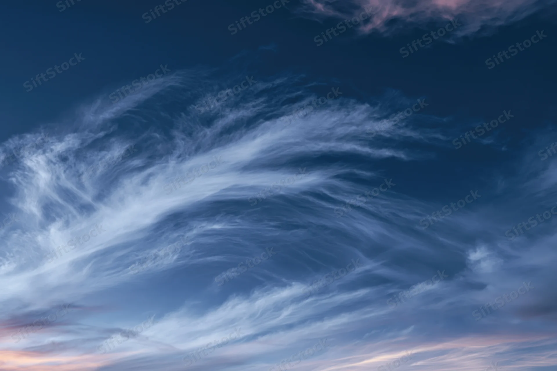Twilight sky with wispy cirrus clouds layered across the horizon