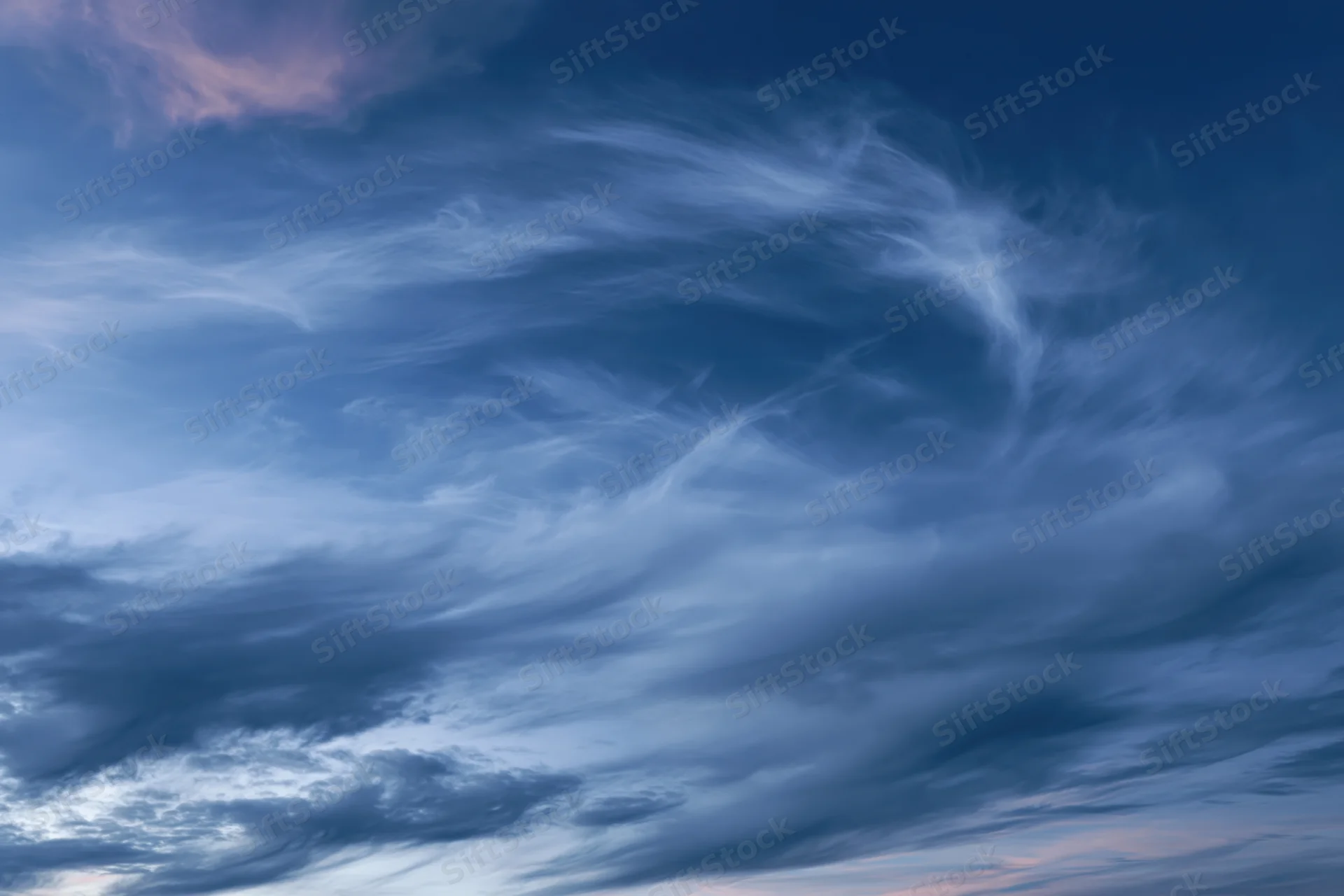 Twilight sky with wispy cirrus clouds layered across the horizon