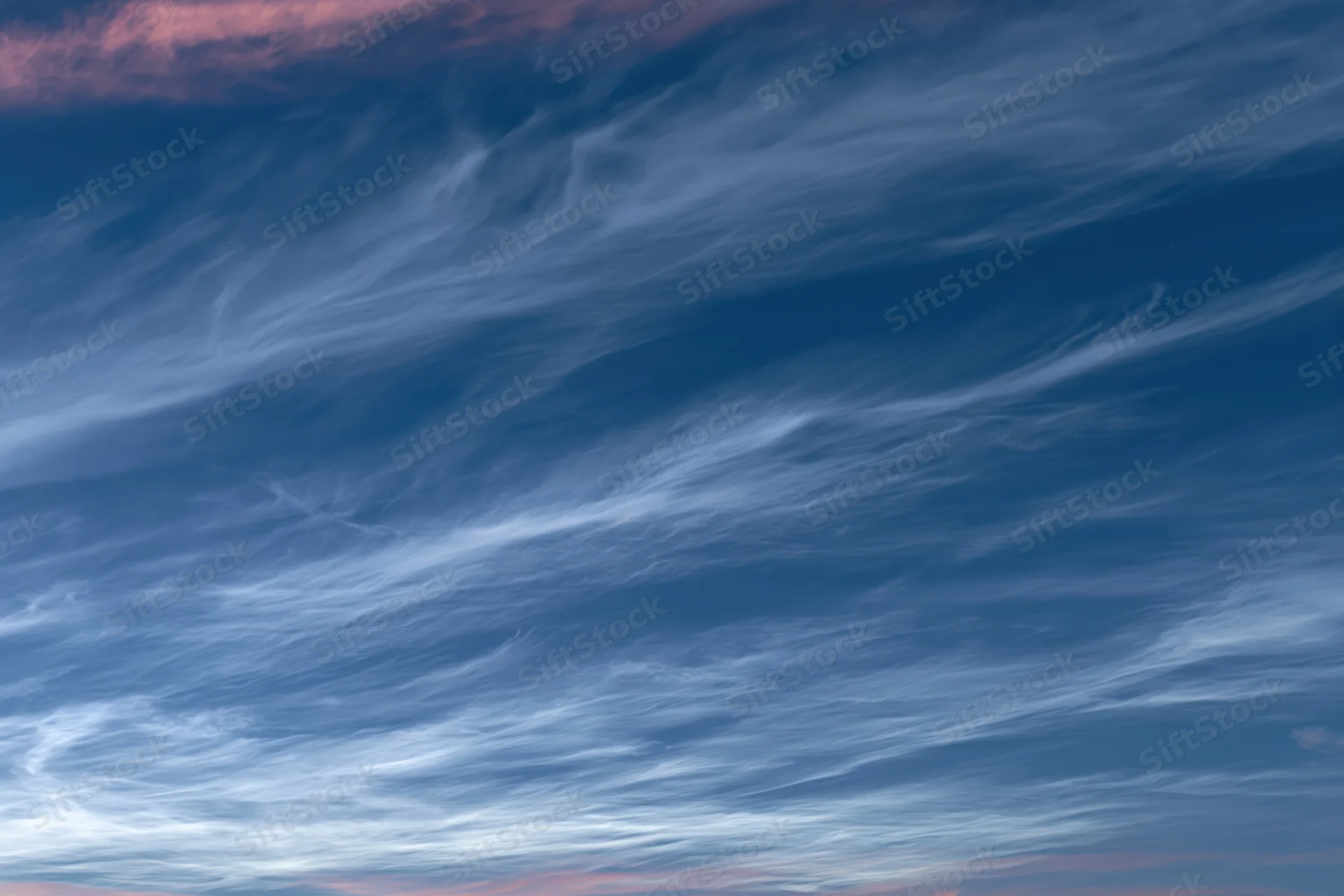 Twilight sky with wispy cirrus clouds layered across the horizon