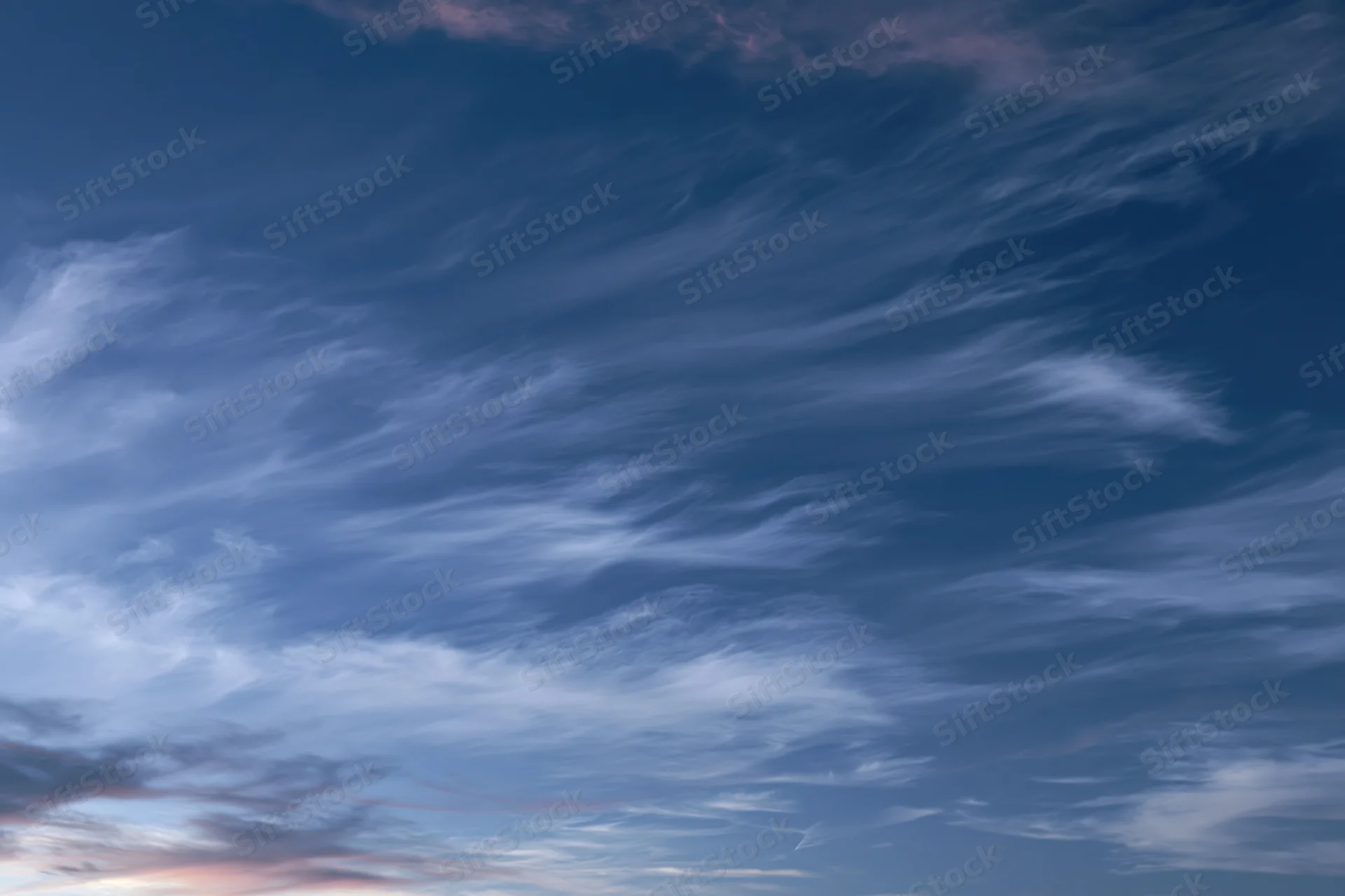 Twilight sky with wispy cirrus clouds layered across the horizon