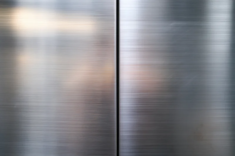 Two brushed stainless steel panels meeting at a vertical seam