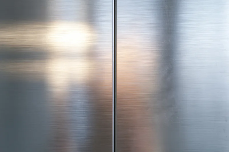 Two brushed stainless steel panels meeting at a vertical seam