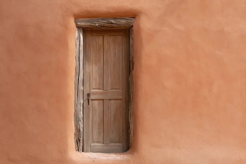 Weathered wooden panel door set into thick adobe wall