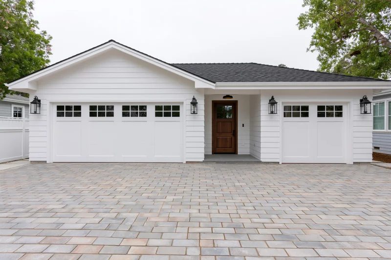 White craftsman-style house exterior with double garages and paved driveway