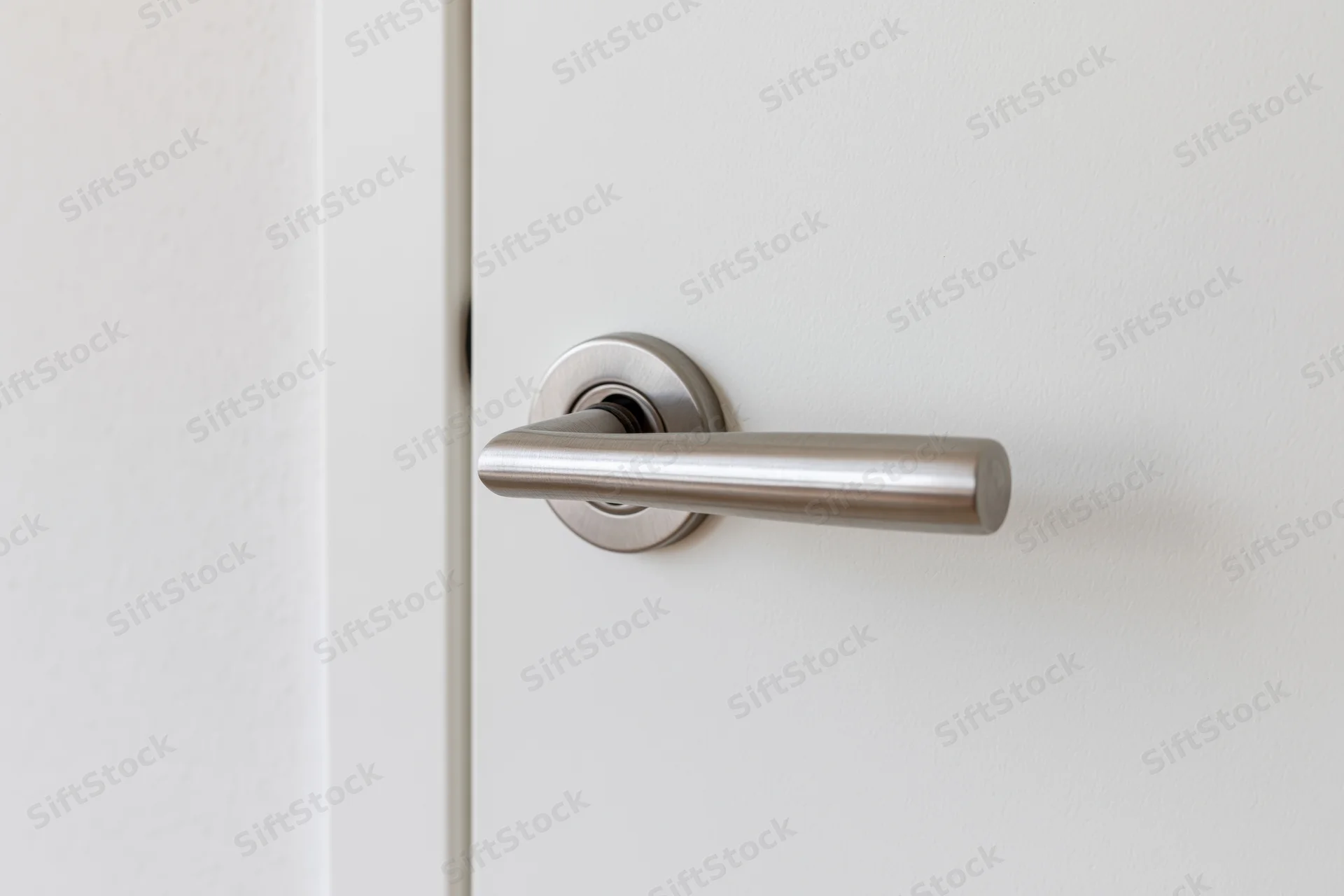 Closeup of a brushed stainless steel lever handle on a white interior door