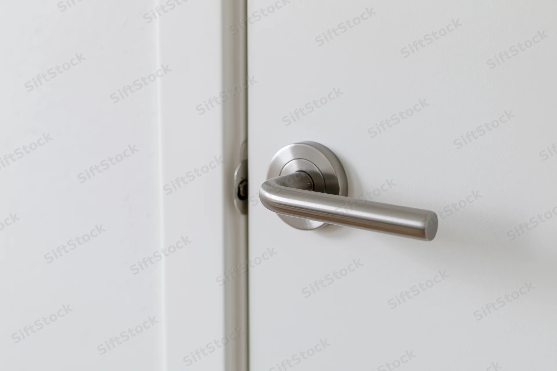 Closeup of a brushed stainless steel lever handle on a white interior door