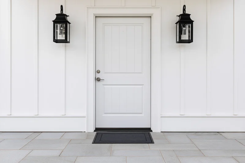 White front door with raised panel design centered on a house exterior