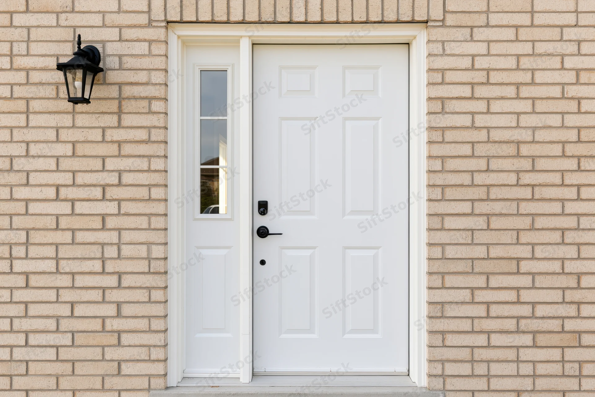 White six-panel front door with sidelite window set in beige brick exterior of a house