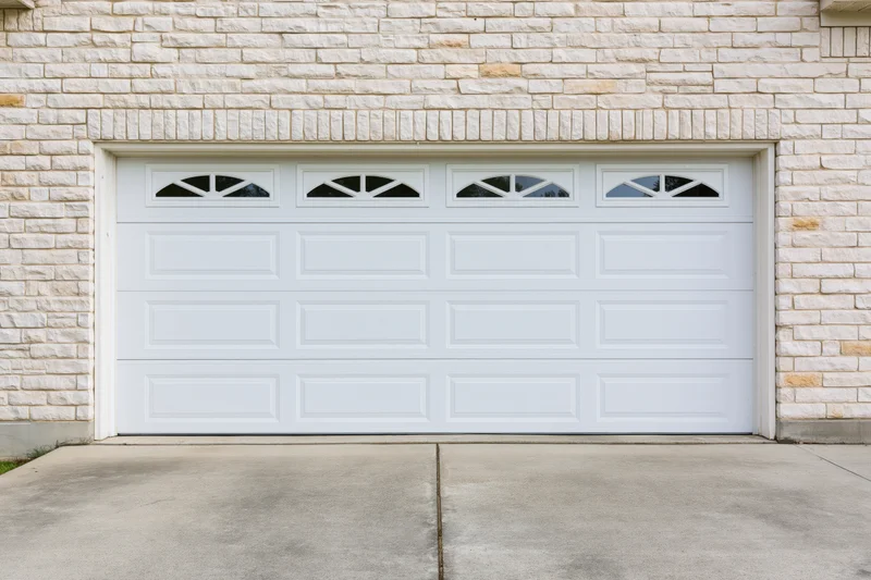 White two-car garage door with raised panels on a stone-clad house exterior