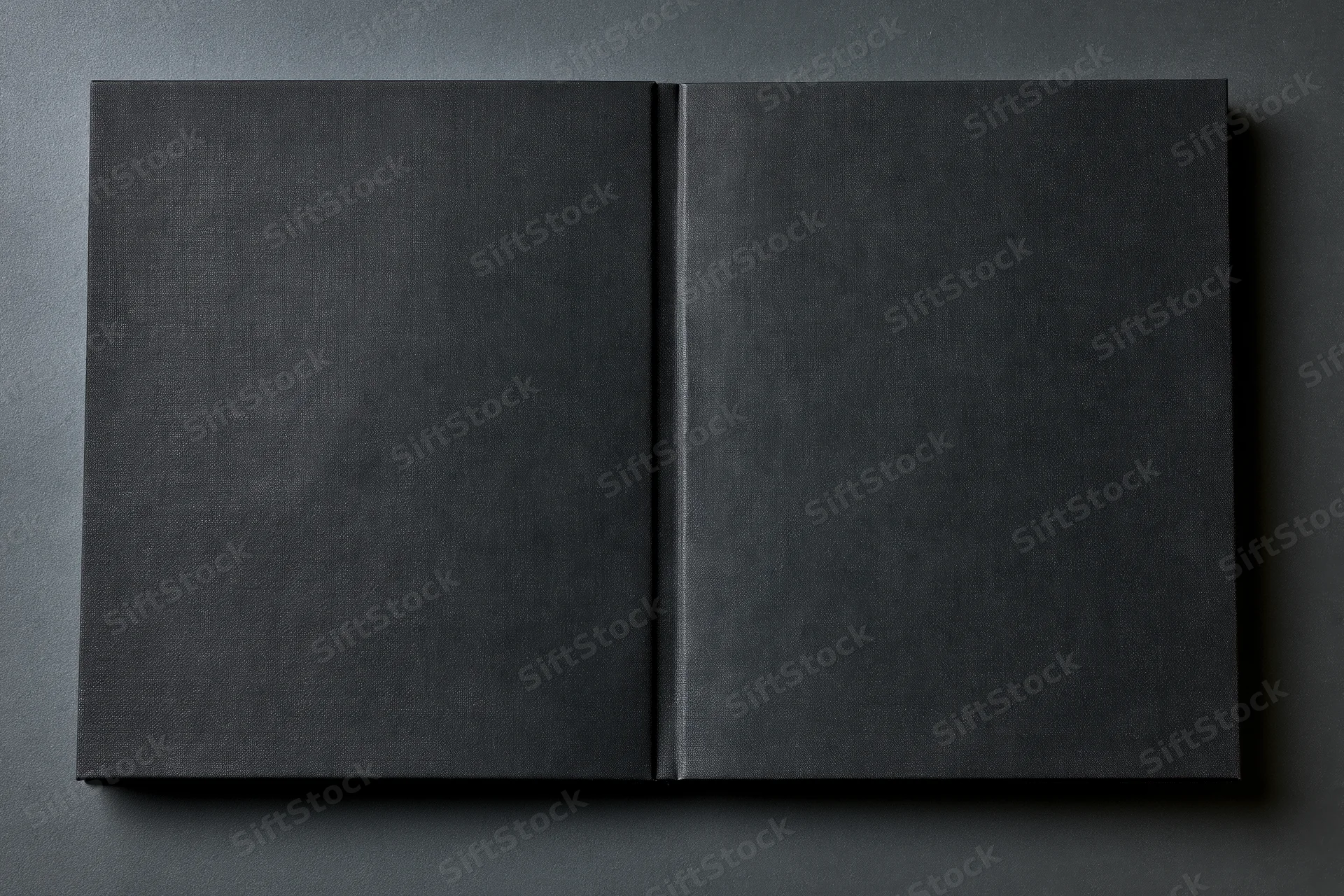 Open black hardcover book lying flat on dark gray surface