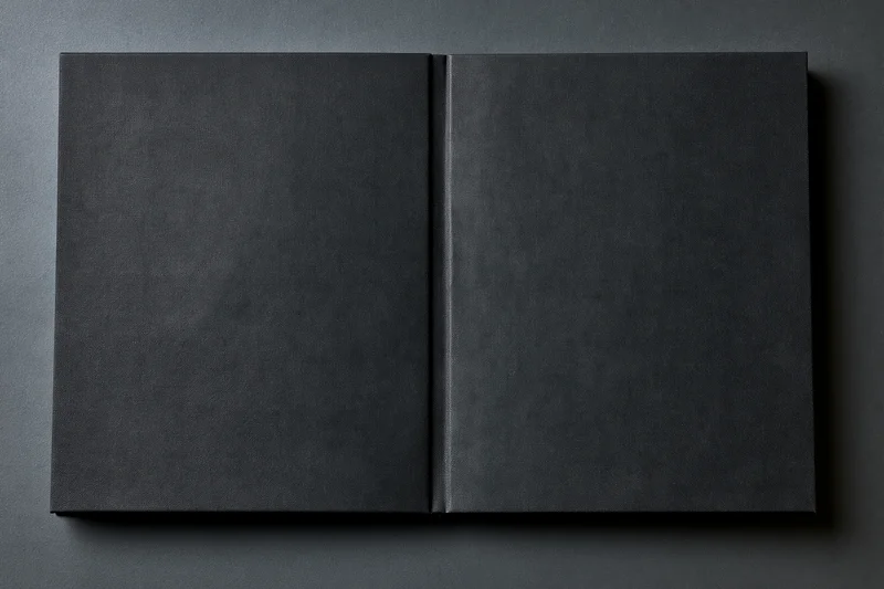 Open black hardcover book lying flat on dark gray surface
