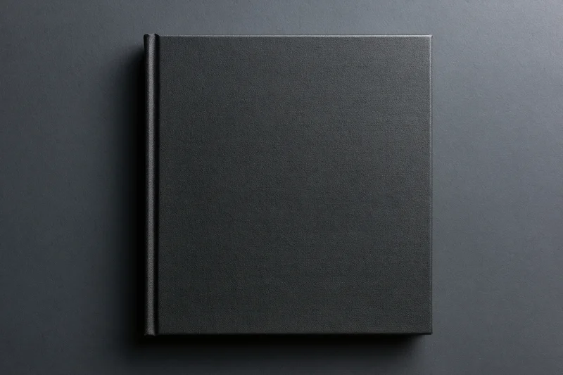 Black hardcover book lying flat on dark surface