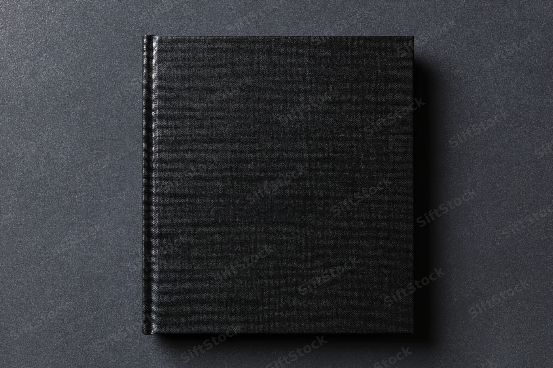 Black hardcover book lying flat centered on dark textured surface
