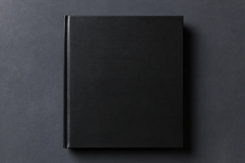 Black hardcover book lying flat centered on dark textured surface