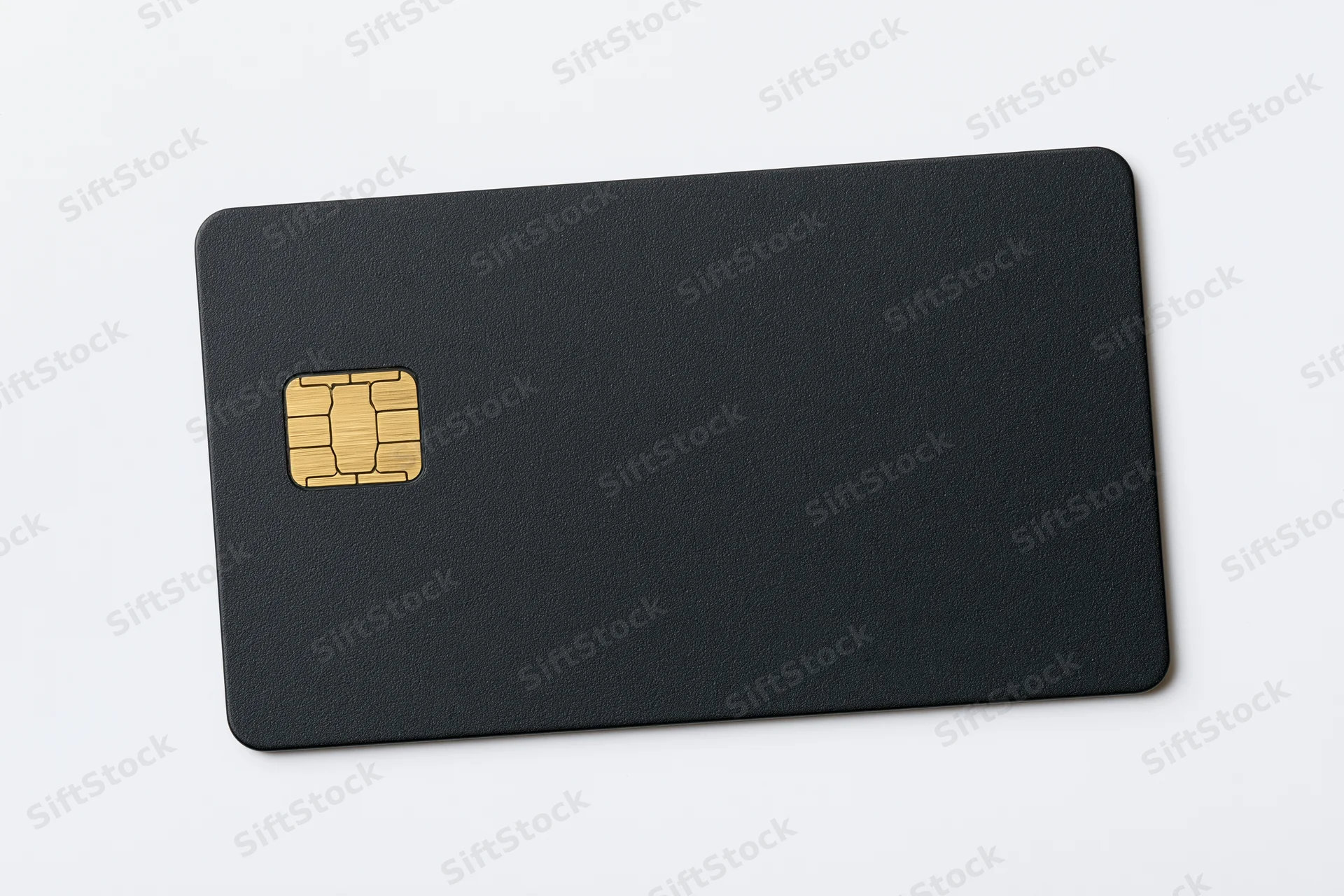 Matte black credit card with gold chip lying flat on white surface