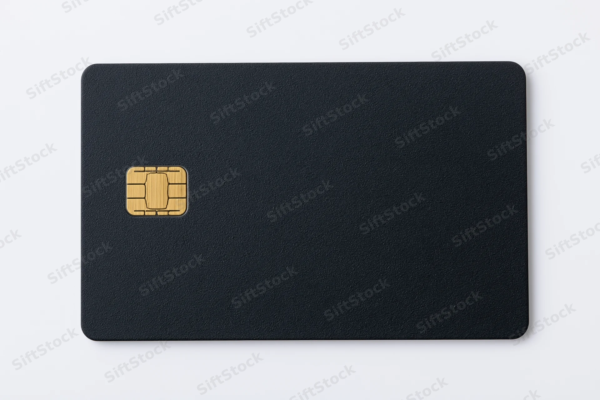 Matte black credit card with gold chip lying flat on white surface