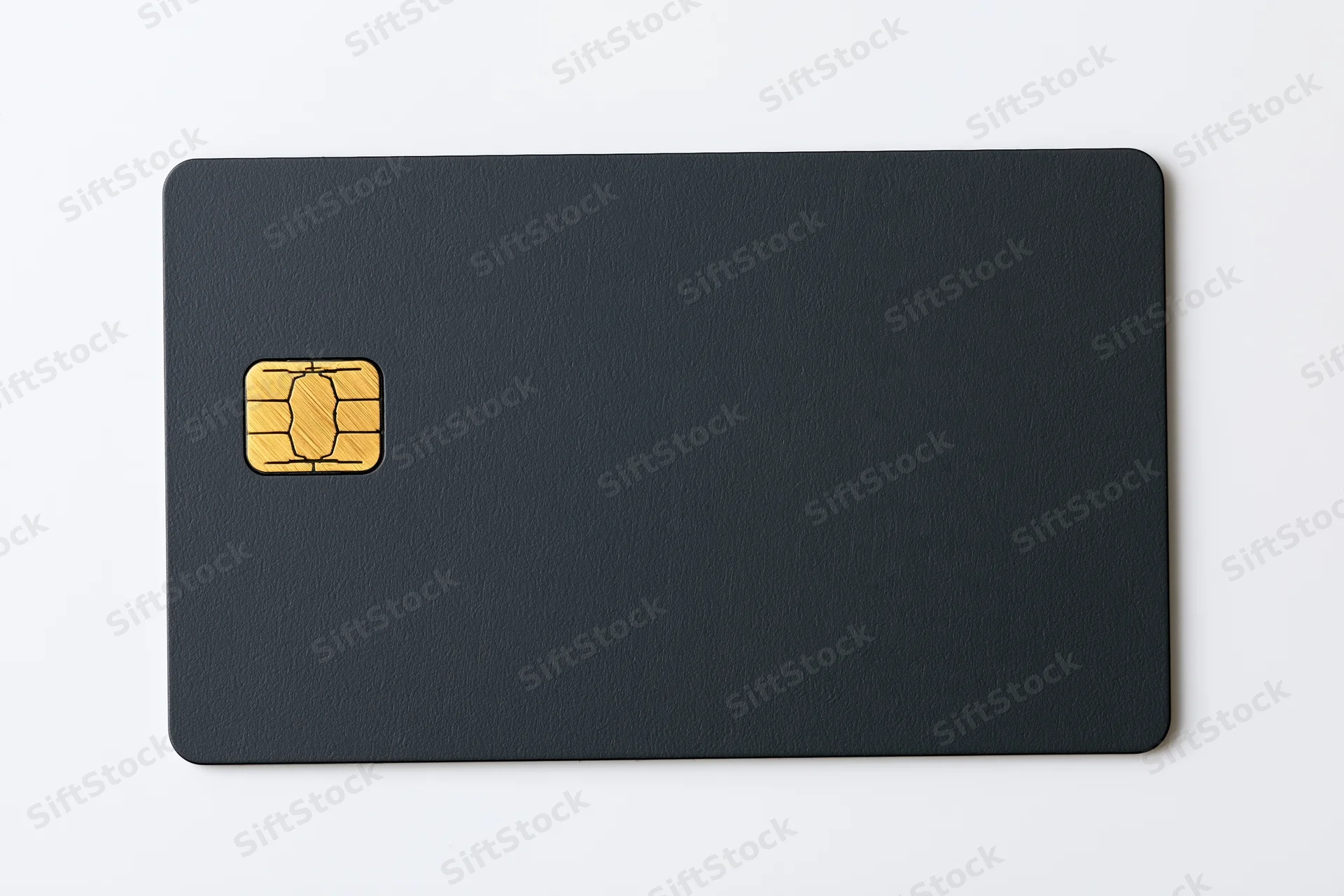 Matte black credit card with gold chip lying flat on white surface