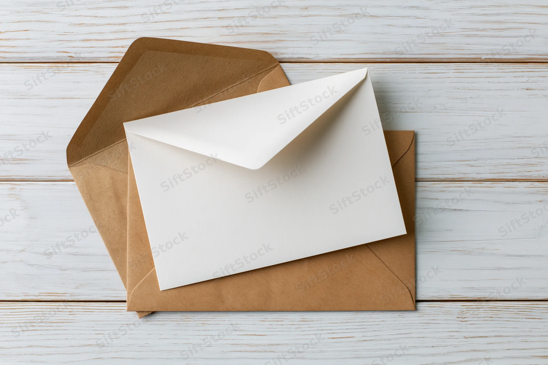 White card resting on kraft envelope on whitewashed wooden surface
