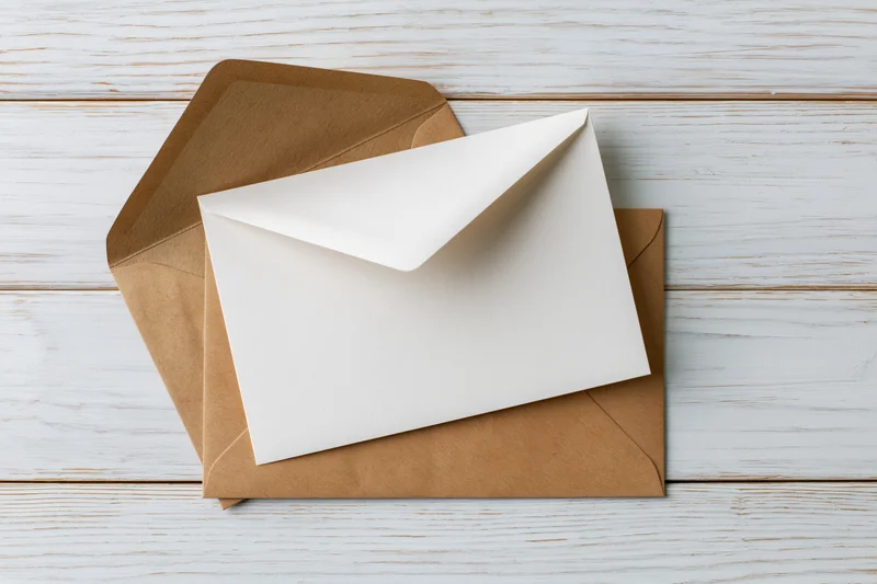 White card resting on kraft envelope on whitewashed wooden surface