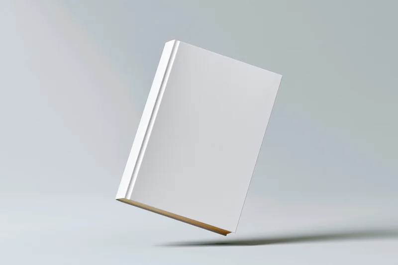Blank white hardcover book standing slightly tilted on a neutral gray surface
