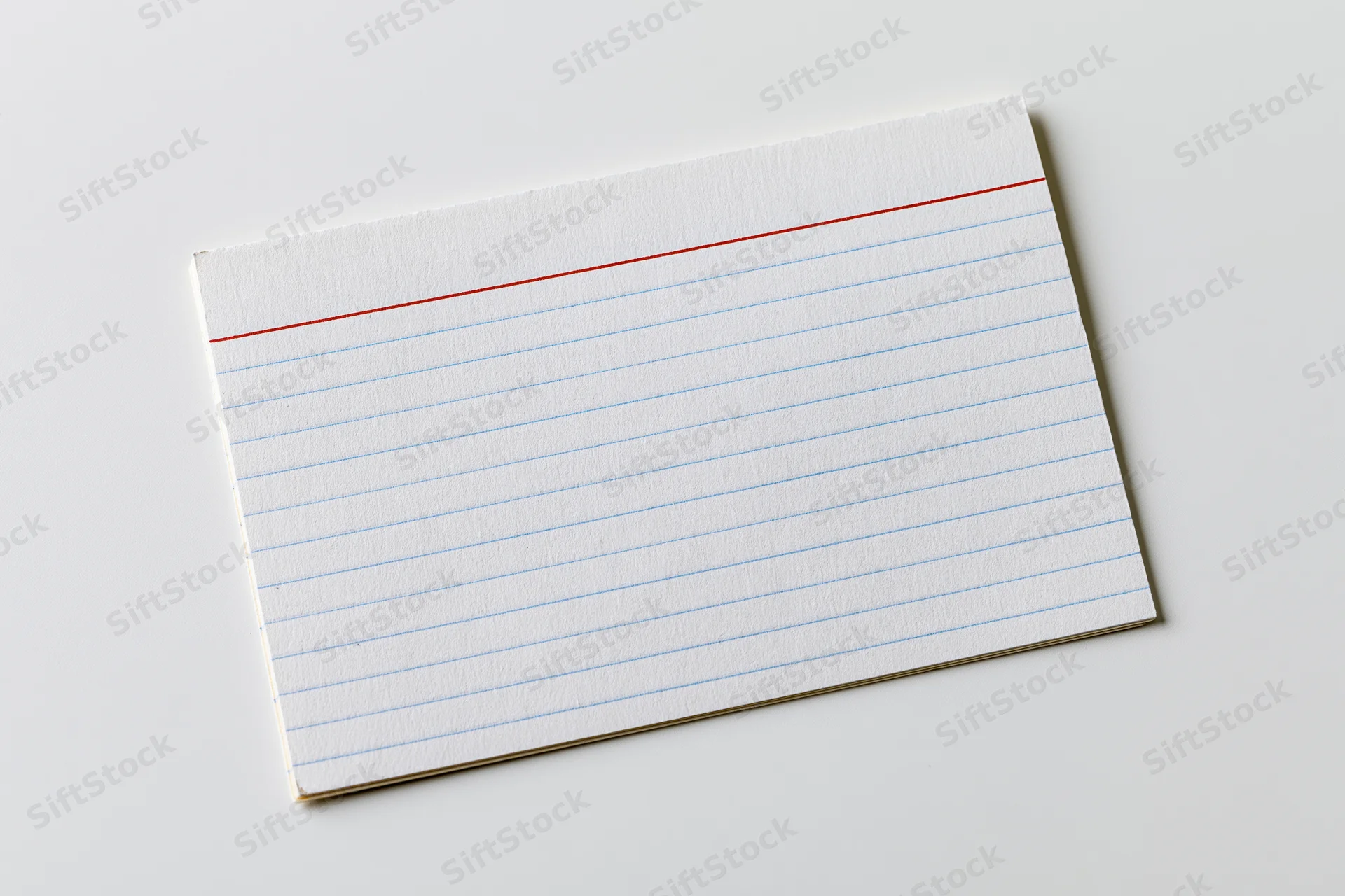 Blank ruled index card lying flat on white surface