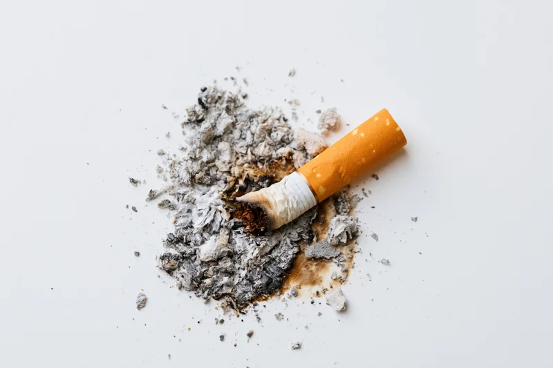 Cigarette stub with ash on white surface