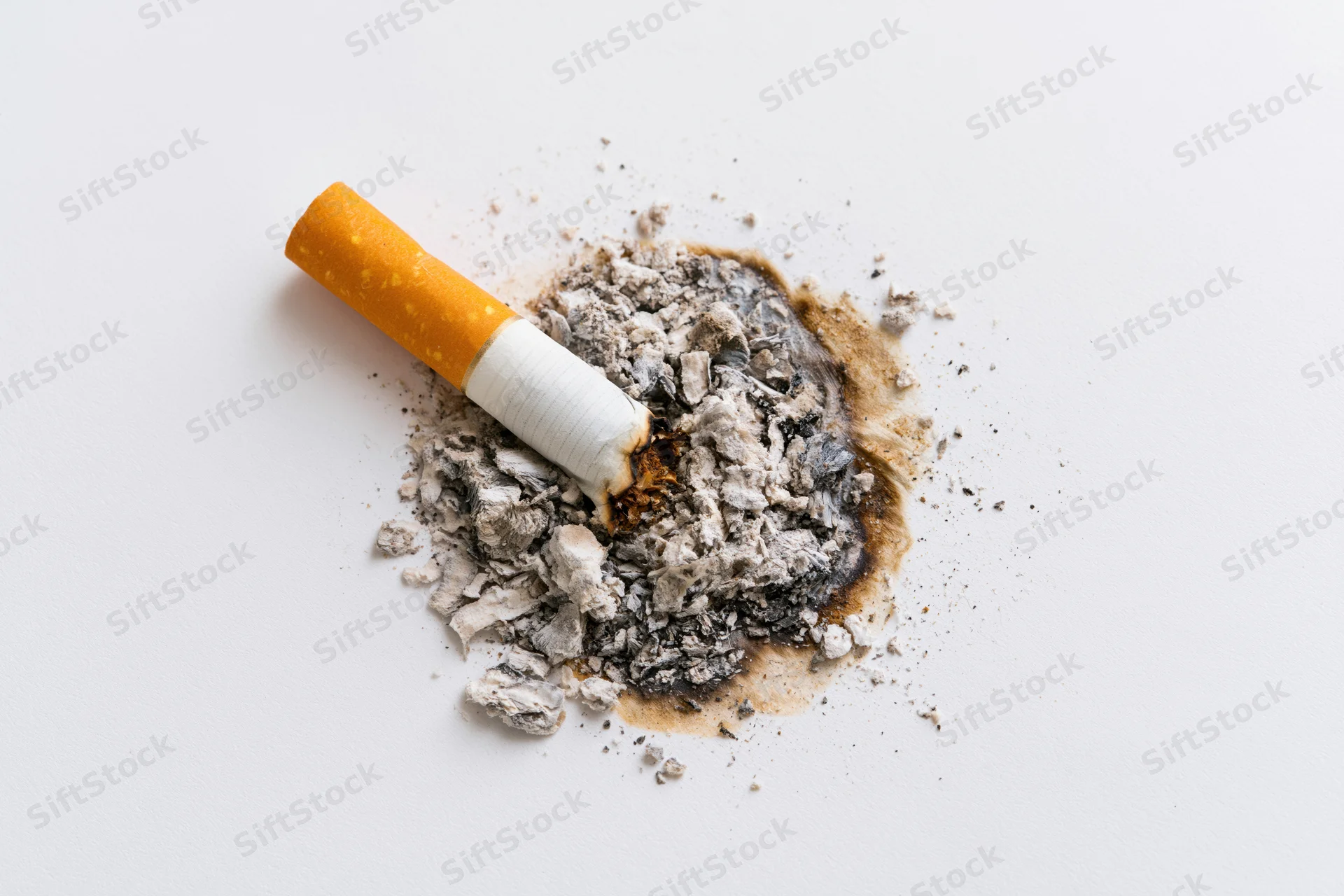 Cigarette stub with ash and burnt residue on white surface