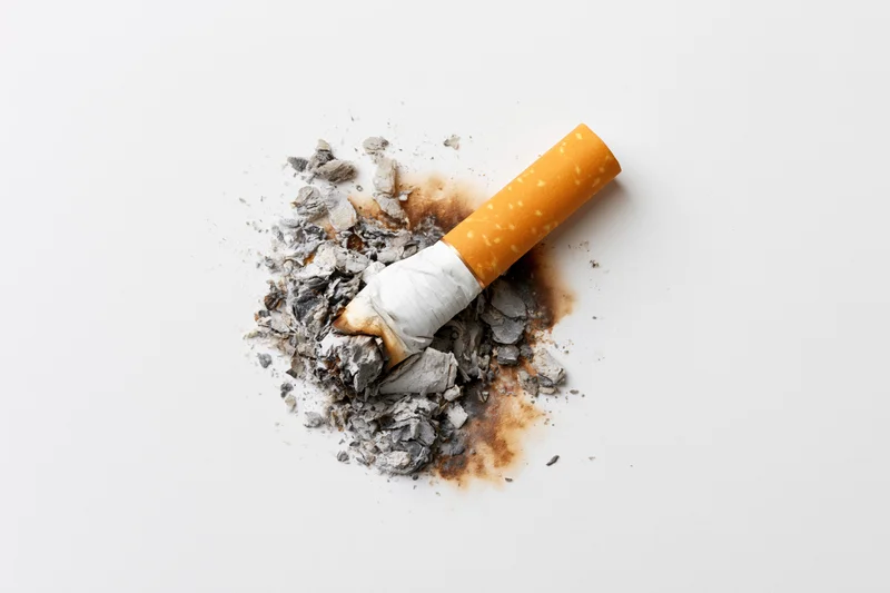 Cigarette stub with ash on white surface