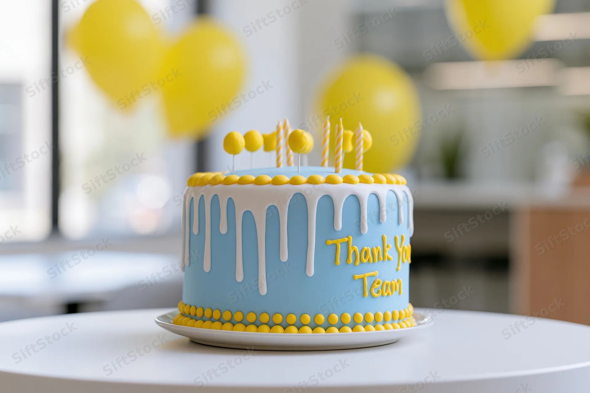 Blue and yellow decorated cake with thank you team message on white table in office setting with balloons