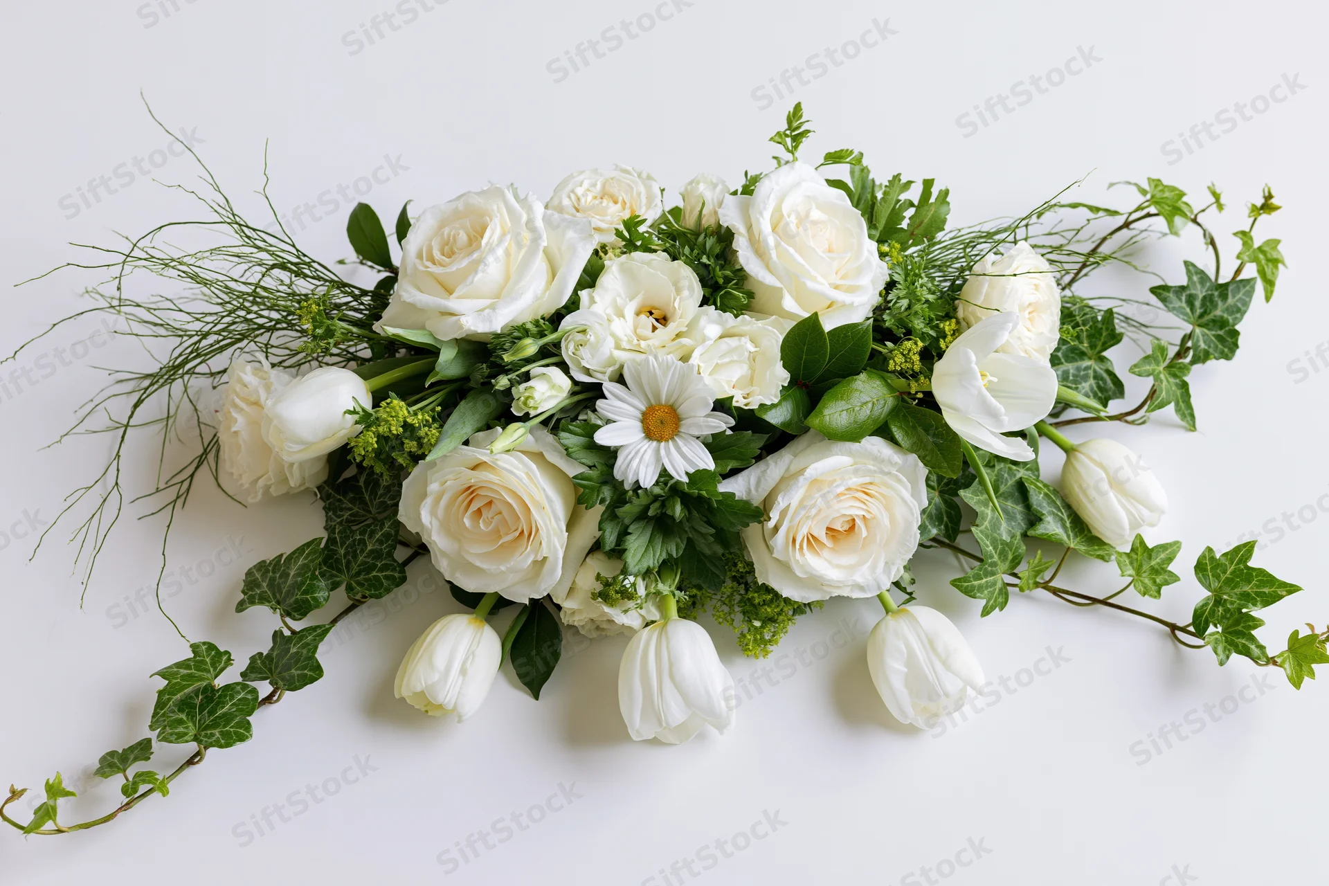 Horizontal floral arrangement of white roses and tulips with green ivy and daisies on white background
