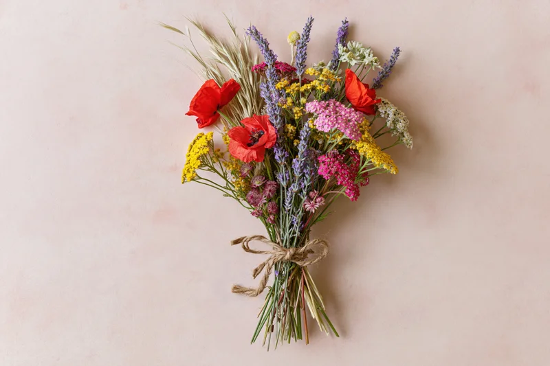 Loose wildflower bouquet tied with twine lying flat on pale pink surface