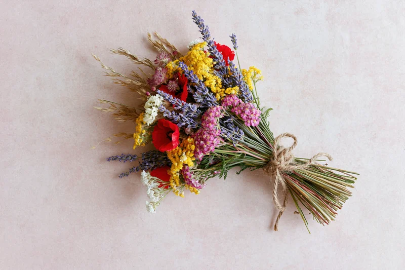 Dried wildflower bouquet tied with twine lying flat on blush pink surface