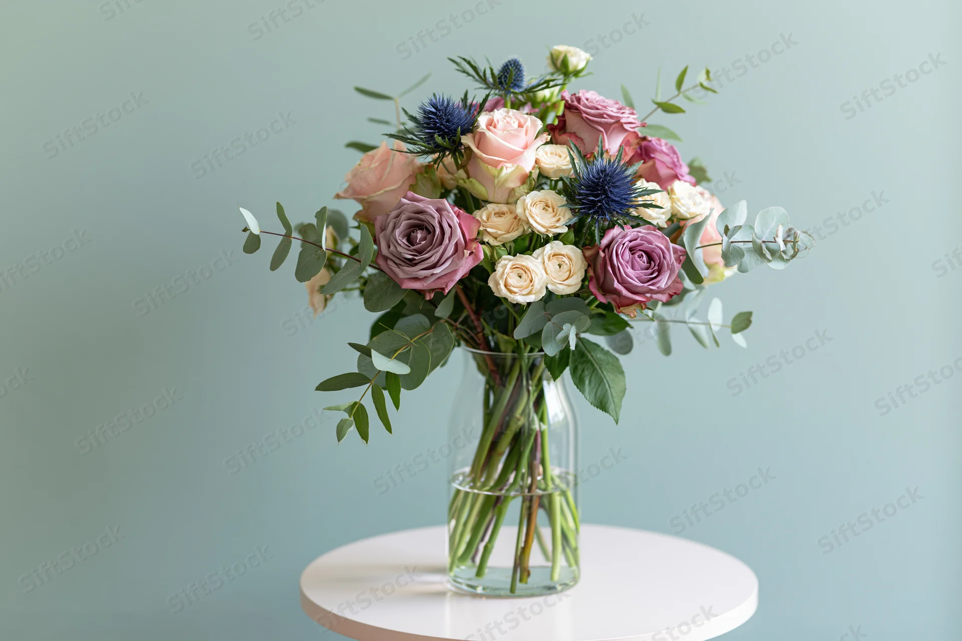 Mixed flower bouquet in a clear glass vase on a white round table