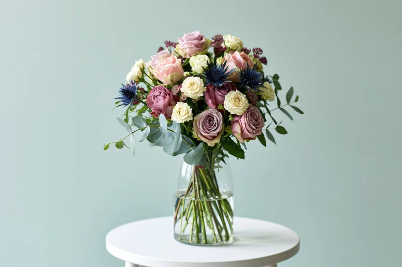 Mixed flower bouquet in a clear glass vase on a white round table