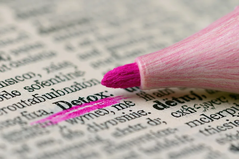Pink highlighter marking the word detox in a printed dictionary page