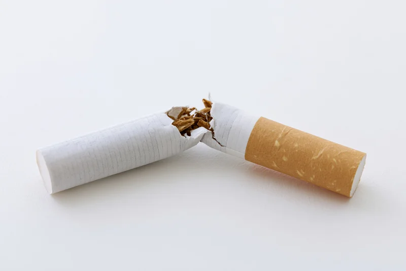 Broken cigarette snapped in half on white surface