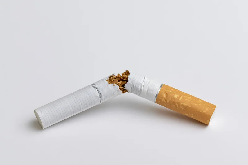 Broken cigarette snapped in half lying on white surface