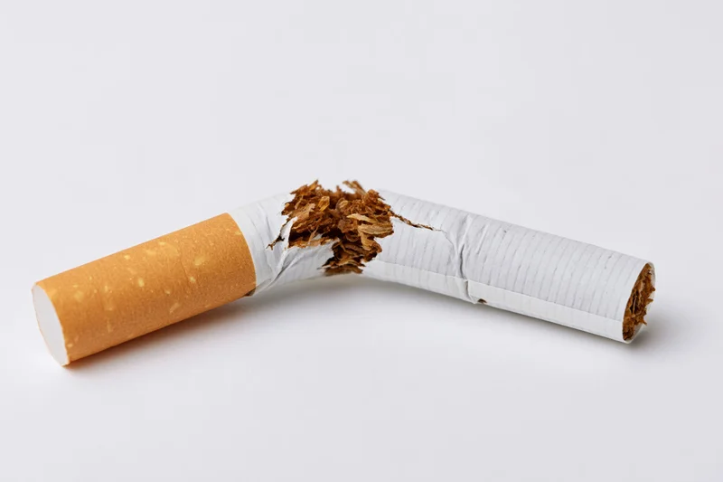 Broken cigarette snapped in half lying on white surface