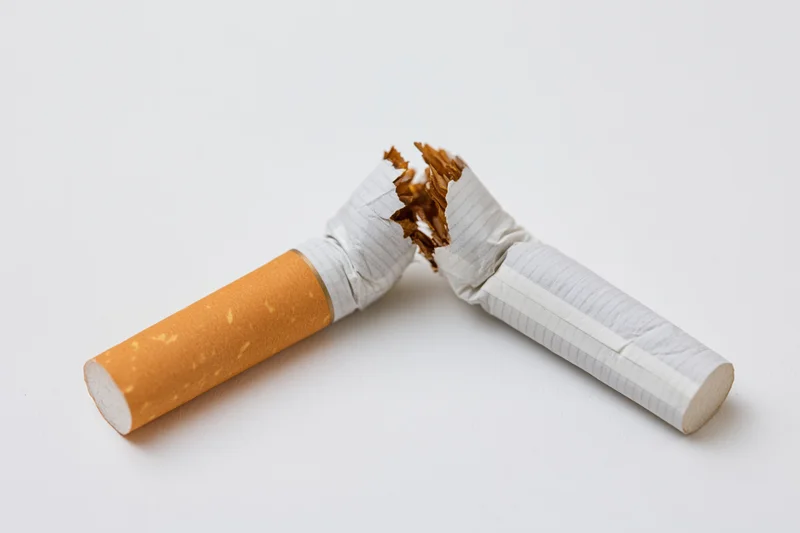 Broken cigarette snapped in half lying on white surface